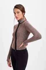 Campera corta de tejido de punto acanalado con diseño de rayas verticales en dos tonos. Presenta cuello alto y cierre frontal completo con borde en color negro.