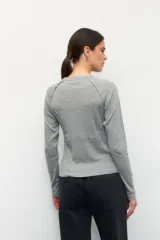 Remera de manga larga color blanco, confeccionada en algodón, con cuello redondo y diseño de costuras decorativas externas que realzan la silueta.