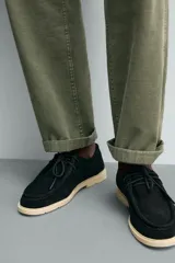 Zapato casual de cordones para hombre, confeccionado en piel con acabado serraje de color negro. Presenta detalle de bordón en el empeine, horma redonda y suela plana en contraste de color beige.
