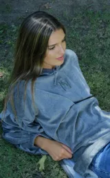 Buzo tipo canguro oversize de plush color verde militar, con capucha, mangas abullonadas con puños elásticos, bolsillo frontal tipo parche y cordón de ajuste en el ruedo. Presenta bordado en el pecho.