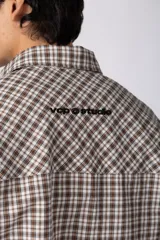 Camisa de manga corta de popelina con patrón a cuadros, calce boxy y largo a la cintura, con bolsillos y canesú cortados en diagonal.