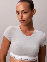 Bralette tipo t-shirt de Calvin Klein, confeccionado en una mezcla de algodón y modal. Presenta cuello redondo, mangas cortas y una banda elástica inferior con el logo de la marca estampado.