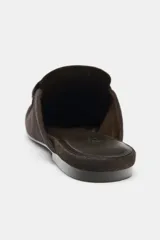 Mocasín destalonado de piel color marrón oscuro, con detalle fruncido en la parte delantera, copete subido y detalle de antifaz. Acabado en punta redonda y suela plana.