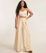 Blusa cropped de sastrería color beige, con escote corazón, breteles anchos con aros metálicos y cierre en la espalda.