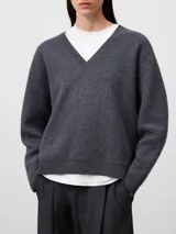 Jersey de lana gris melange con cuello en pico, manga larga y diseño de corte holgado con terminaciones en canalé en puños y ruedo.