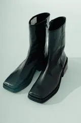 Bota de caña media confeccionada en cuero negro, con diseño minimalista, punta cuadrada y taco ancho geométrico.