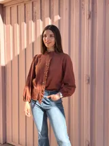 Camisa de manga larga color marrón chocolate, con cuello alto y detalles de volados a lo largo de la botonadura frontal.