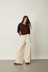 Jean azul oscuro de corte wide leg y tiro alto, con costuras pespunteadas verticales al frente y cinturón incorporado con hebilla cuadrada.