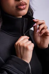 Buzo negro con cierre de media cremallera, cuello alto y logo bordado en el pecho.