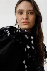 Chaleco negro de lana merino con flecos bordados a mano en los hombros.