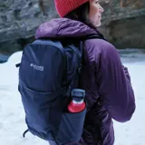 Mochila Columbia modelo Triple Canyon 24L con tecnología Omni-Shield, color negro. Cuenta con bolsillos laterales para botellas, compartimento principal con cierre, panel trasero de malla transpirable y tirantes acolchados.