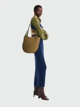 Cartera tipo hobo de gran tamaño, confeccionada en cuero con textura granulada. Presenta un diseño de silueta curva y minimalista con una correa de hombro integrada y cierre superior.