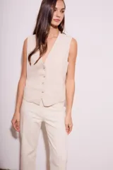 Chaleco de corte sastre con escote en V y cierre frontal de botones. Presenta un diseño sin mangas, entallado al cuerpo, confeccionado en una mezcla de lino y viscosa.