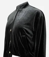 Campera bomber de terciopelo color verde oscuro, con cuello redondo, cierre frontal con botones metálicos, bolsillos laterales y mangas largas con puños elásticos.