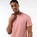 Camiseta de cuello redondo y manga corta color rosado, con textura en nido de abeja y pequeña etiqueta decorativa en el dobladillo.