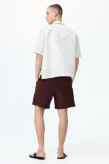Short de corte relaxed fit confeccionado en suave tejido texturizado de mezcla de viscosa, en color bordó. Cuenta con cintura elástica con cordón ajustable, bolsillos laterales discretos y un bolsillo trasero ojal.