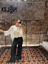 Blusa blanca de encaje con diseño de flores pequeñas entrelazadas, de corte holgado y mangas tres cuartos.