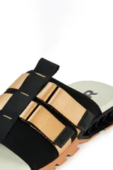 Sandalias Kenner Rakka Yaki con base color hueso, suela marrón y tiras de tela negra con apliques de cuero sintético color beige.