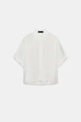 Camisa fluida de cuello solapa y manga corta con dobladillo. Presenta un diseño minimalista con cierre frontal de botones ocultos por tapeta.