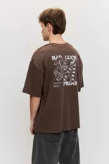 Remera marrón oversize de manga corta, con cuello redondo y pequeños estampados blancos en el pecho.