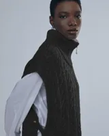 Chaleco de punto negro con cuello alto y cierre frontal con cremallera.