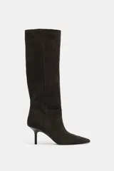 Bota de caña alta confeccionada en serraje, con diseño de punta fina y tacón fino. Presenta detalle de pespuntes en el cuerpo y sistema de calce pull-on.