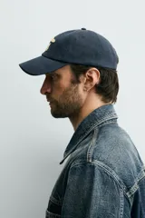Gorra de seis paneles azul marino confeccionada en tejido de algodón, con bordado frontal en tono contrastante con la leyenda "button 84".