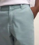 Bermuda masculina de sarga en color blanco, con cierre frontal de botón y cremallera, trabillas para cinturón y bolsillos laterales.