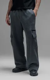 Pantalón tipo jogger gris melange de corte baggy y silueta amplia, confeccionado en frisa de algodón. Presenta cintura elástica, bolsillos laterales de mano y bolsillos estilo cargo con solapa y cierre en los laterales.