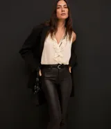 Pantalón bootcut Cortelle de sarga resinada color negro, con cintura mediana, bolsillos delanteros y traseros, cierre con botón y cremallera, y trabillas en la cintura.