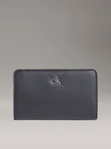 Billetera plegable Calvin Klein de piel sintética negra, con diseño minimalista y monograma metálico 'ck' en el frente. Cuenta con protección RFID, múltiples ranuras para tarjetas y compartimentos de seguridad.