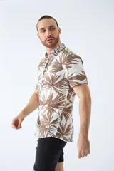 Camisa de manga corta con estampado botánico de hojas en tonos azul y blanco. Presenta cuello clásico, cierre frontal abotonado y corte slim.