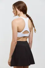 Top deportivo corto de sujeción media, con escote redondo clásico y espalda abierta. Presenta un diseño al cuerpo con elástico interno en la cintura.