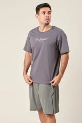 Bermuda deportiva de nylon color gris, de corte suelto, con cintura elástica y cordón de ajuste. Cuenta con detalles de líneas en los costados y bolsillos con cierre.