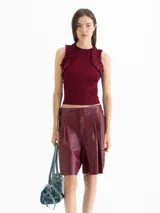 Top de tejido de punto color bordó, con cuello redondo, ajuste al cuerpo y volados decorativos en las sisas.