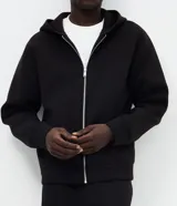 Campera bomber con capucha, confeccionada en tejido técnico estructurado. Presenta cierre frontal completo con cremallera metálica, bolsillos laterales y puños con elástico. Diseño versátil de corte estándar.
