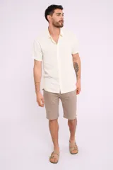 Camisa de manga corta color crudo, con cuello camisero y abotonadura frontal.