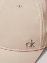 Gorra de béisbol color beige claro, confeccionada en sarga de algodón orgánico, con visera curva y herraje metálico con el monograma 'ck' en el frente.