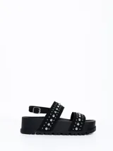 Sandalia chunky de plataforma color negro, con diseño de doble tira ancha decorada con tachas metálicas cónicas y pulsera ajustable al tobillo con hebilla.