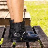 Bota corta negra de cuero vacuno con estribo desmontable, suela de caucho, cierre interno y punta redonda.