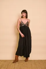 Vestido largo negro con tirantes finos, escote en V y el busto bordado con lentejuelas. Presenta líneas de bordados verticales a lo largo de la falda fluida.