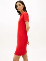 Vestido tipo chomba de color rojo, con corte slim y largo hasta la rodilla. Cuenta con mangas cortas, cuello polo y escote en V pronunciado. Presenta detalle de logo bordado en la manga.