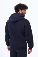 Buzo con capucha y bolsillo frontal tipo canguro, confeccionado en tela de felpa, con cordones ajustables en el cuello y puños elásticos.