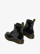 Botas Dr. Martens modelo 1460, de charol negro brillante, con cordones negros, costuras amarillas en la suela y tira trasera con logo AirWair.
