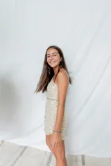 Vestido corto color dorado brillante, de un hombro, con abertura lateral y falda drapeada.