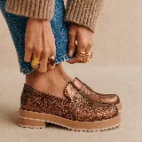 Mocasines de cuero negro con plataforma y suela de goma, decorados con tachas metálicas plateadas en el empeine y el talón.