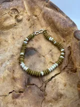 Pulsera de cuentas de madera color verde oliva y cuentas blancas, con cierre de gancho plateado.