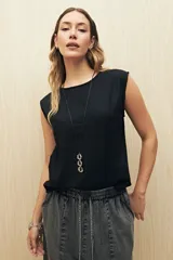 Top sin mangas de lino y viscosa, color negro, con escote redondo y caída relajada. Presenta hombros levemente marcados y botones forrados en la espalda.