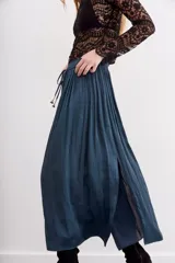 Falda larga de poliéster color azul petróleo, con cintura elastizada tipo nido de abeja, lazos de ajuste con terminales metálicas y tajo lateral.