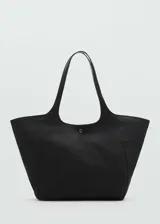 Bolso tipo shopper de tamaño grande, confeccionado en tejido de nylon negro. Presenta doble asa de hombro, cierre principal de cremallera y un cierre metálico a presión en la parte frontal.